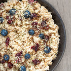 Oatmeal with blueberries and cranberries in a bowl on a wooden surface