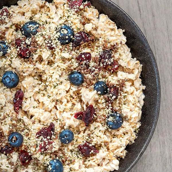 Oatmeal with blueberries and cranberries in a bowl on a wooden surface