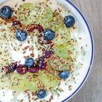 Yogurt bowl with granola, blueberries, and grapes on a wooden surface