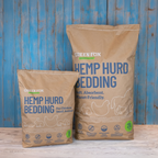 Two bags of Green Fox Hemp Hurd Bedding against a blue wooden background